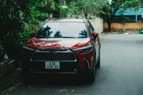 Free A red Toyota Corolla Cross parked outdoors on a quiet street with greenery. Stock Photo