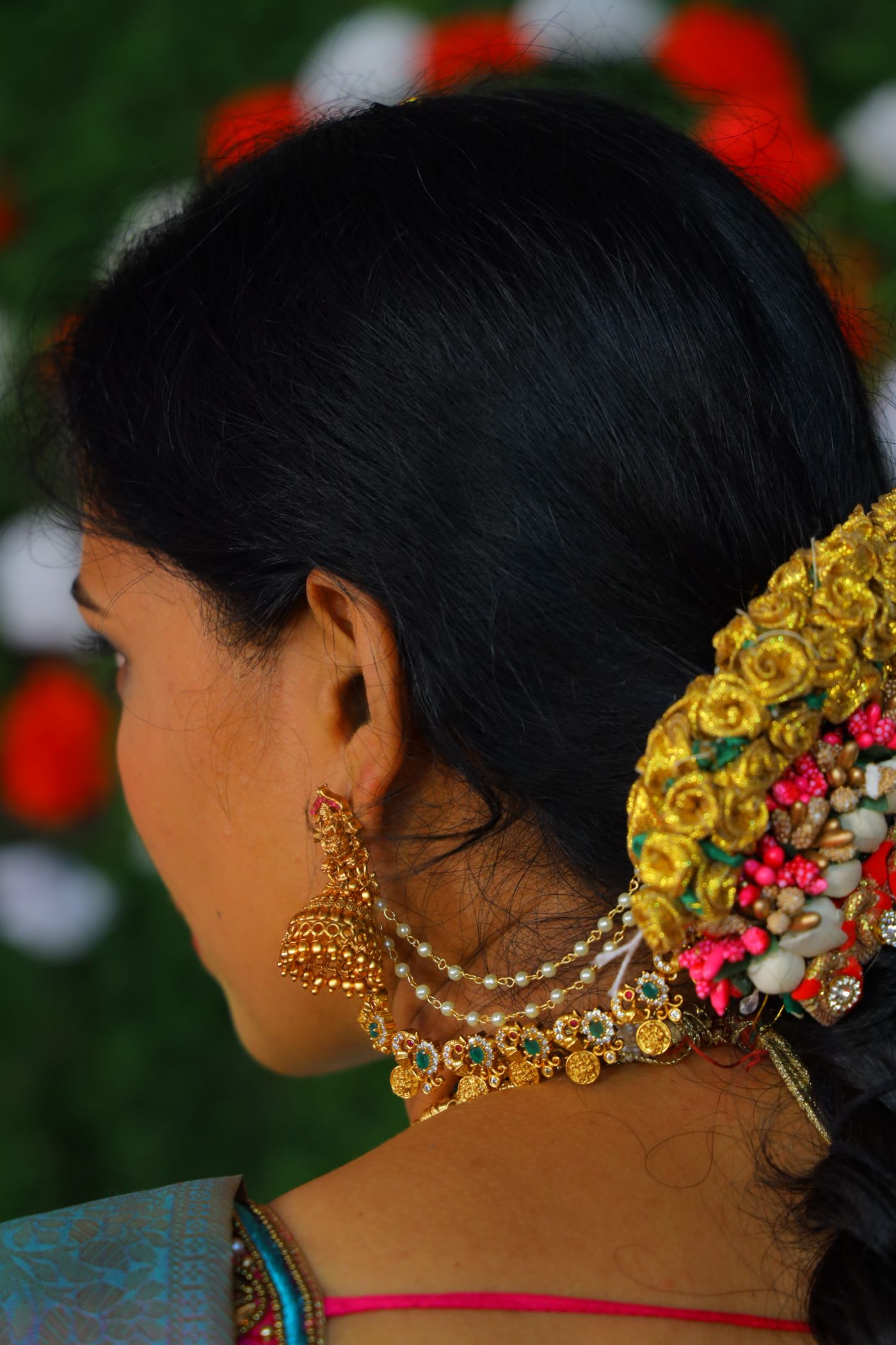 Woman in traditional gold earrings and floral hair ornament