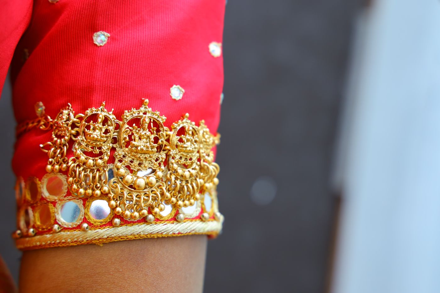 Gold threadwork edging a deep red sleeve