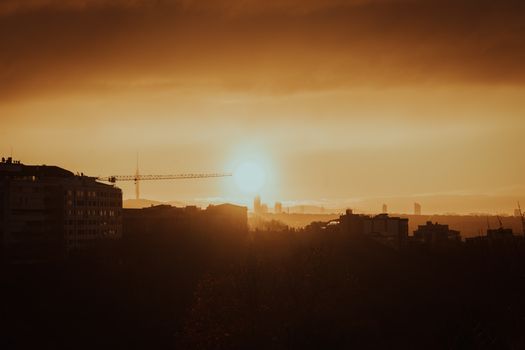 Beautiful sunset over city skyline with silhouette of buildings and crane.