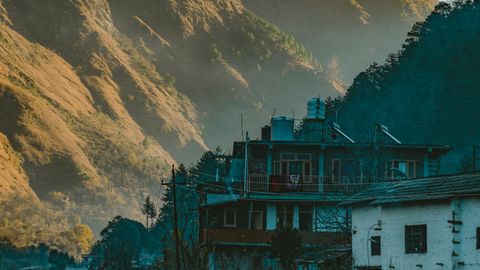 Charming mountain village with rustic houses and dramatic hills at sunrise.