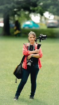 Female photographer with camera and gear in a park setting, capturing moments.