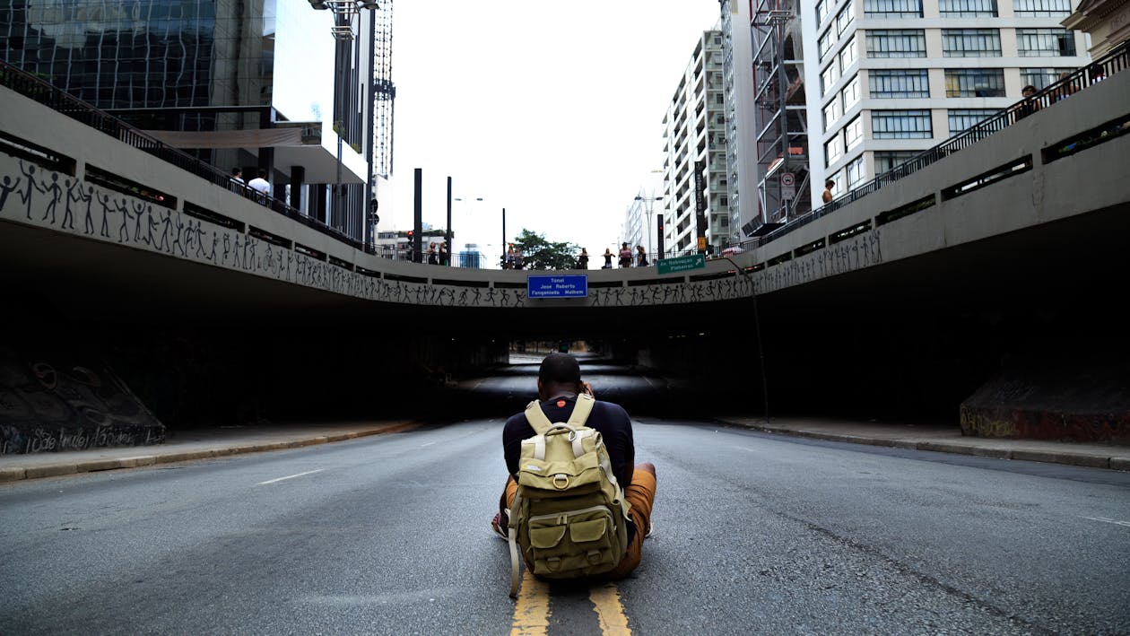 Photo of Man Sitting in Middle of Road