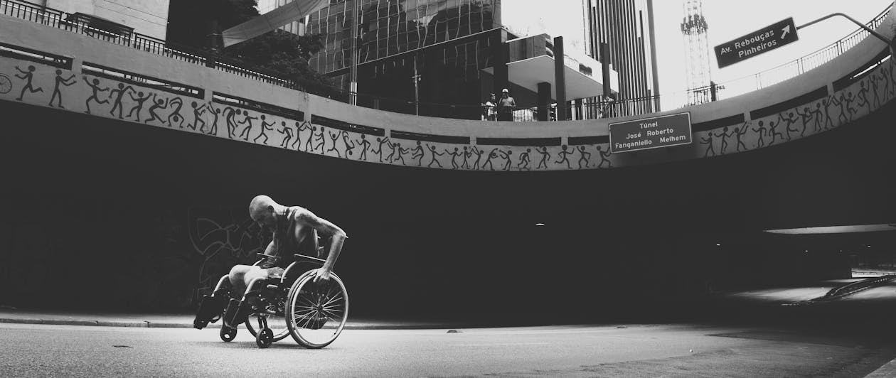Grayscale Photo of Man on Wheelchair