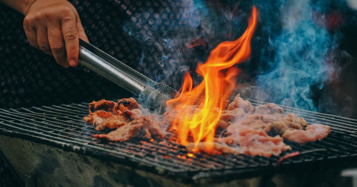 Man grilling outdoors on a sunny afternoon with friends and family in the backyard