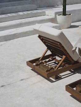 Wooden sunbed basking in tropical sunlight beside minimalist stone steps.