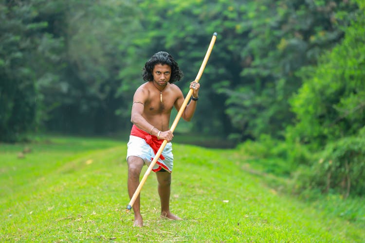 A Shirtless Man Holding A Stick