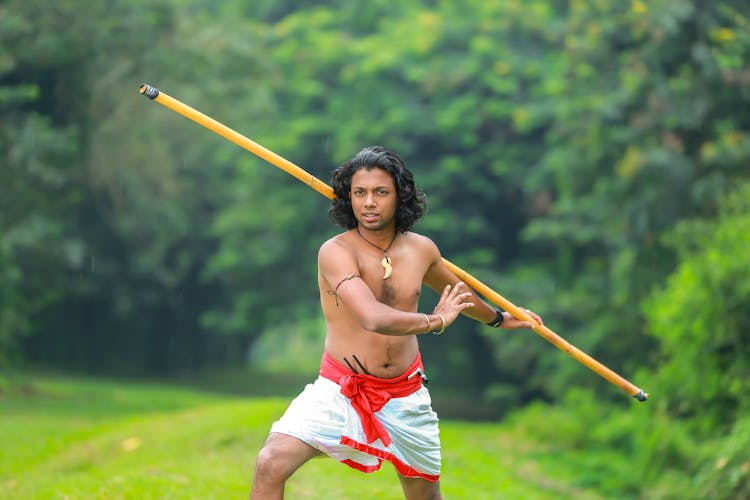 A Shirtless Man Holding A Stick