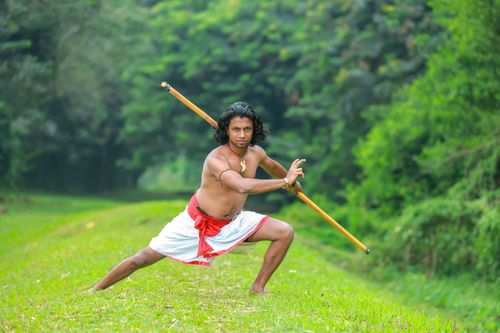 Free Asian man practicing Silambam martial arts outdoors with a bamboo stick. Stock Photo