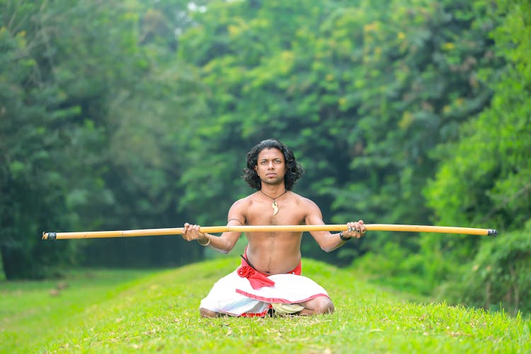 A Shirtless Man Holding A Stick