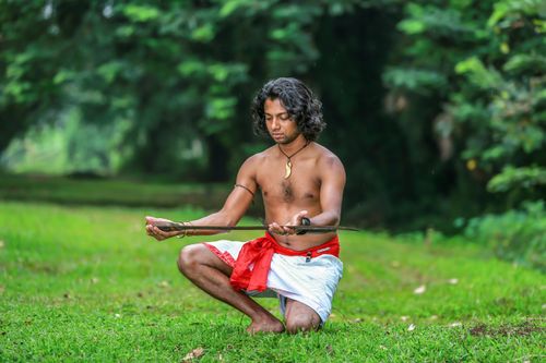 Free A man practicing martial arts with a sword in a vibrant outdoor setting, showcasing traditional attire and focus. Stock Photo