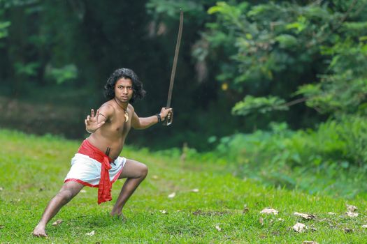 Asian man practicing martial arts with a sword outdoors, showcasing traditional skills and strength.