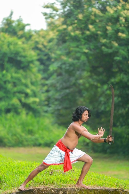 Free An Indian man practicing traditional martial arts outdoors with a sword in Kerala. Stock Photo
