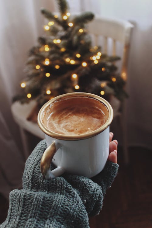 Woman Holding a Cup of Coffee on the Background of a Christmas Tree