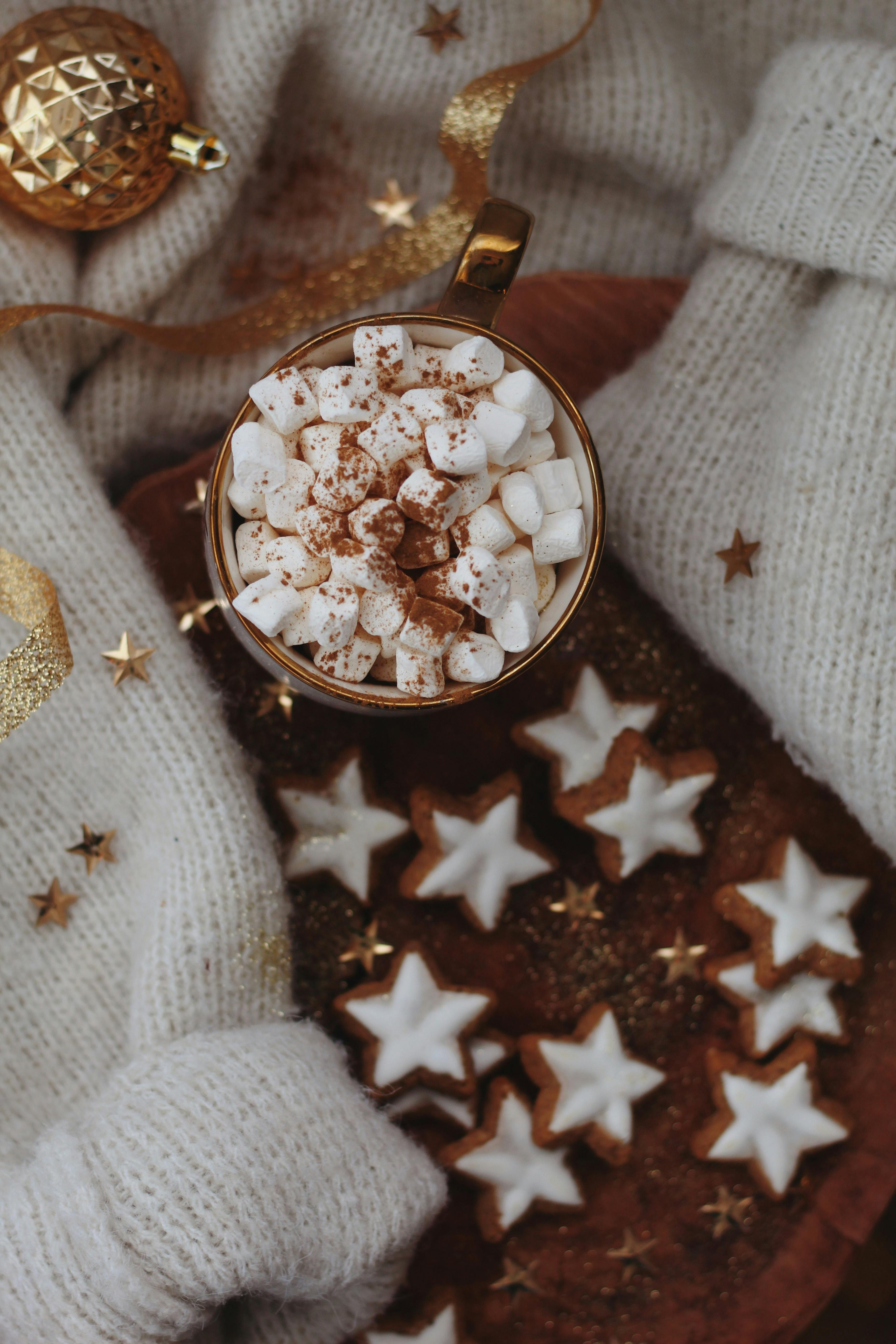 Warm cup of cocoa with marshmallows and star cookies, perfect for winter comfort.