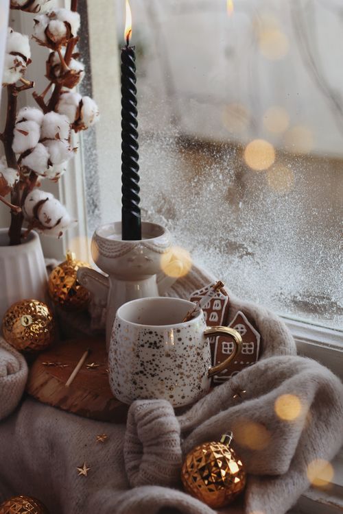 Free Warm and festive winter setup with candle, mug, and gingerbread on a windowsill. Stock Photo