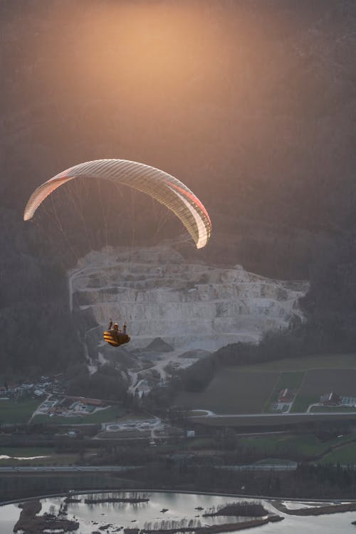 Person Paragliding Over a Body of Water