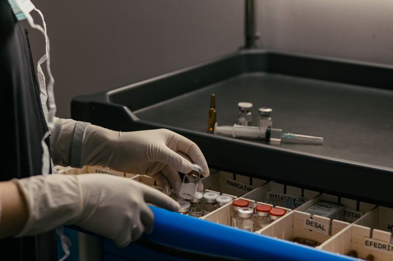 Gloved hands organizing vials in a tray