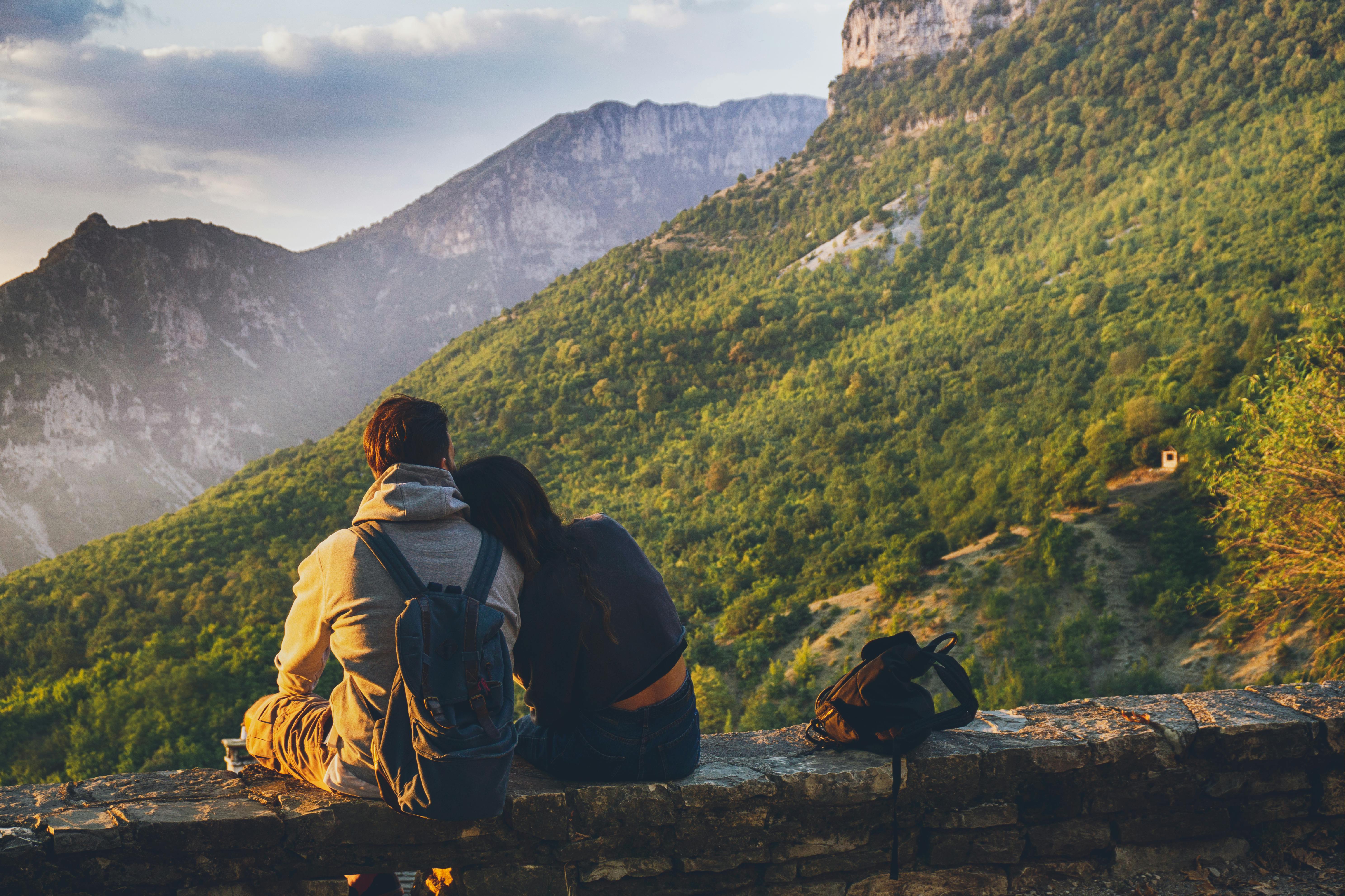 A couple sits facing the mountain. | Photo: Pexels