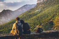 情侣坐在一起欣赏日落时山景优美，体现了爱与冒险