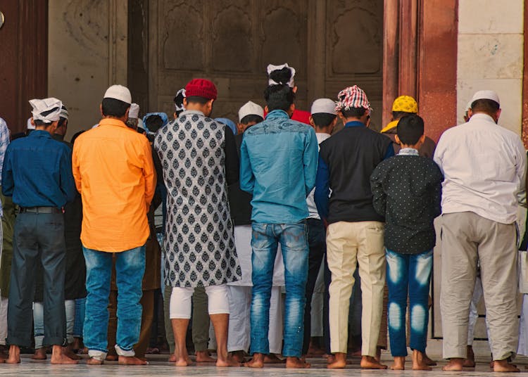 Back View Of A Group Of Men Standing In Front Of A Mosque 