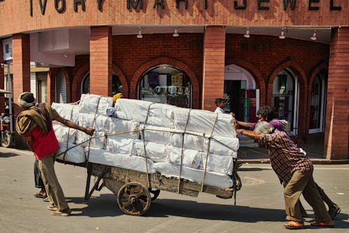 Men Pushing a Fully Loaded Cart on a City Street 