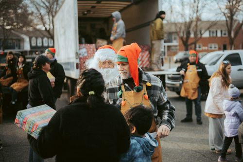 Free Santa and volunteers distribute gifts from a truck in a community Christmas event. Stock Photo