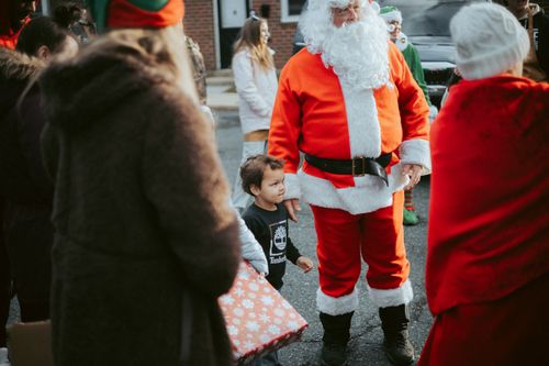 Free A joyful outdoor celebration featuring Santa Claus interacting with children in a lively street setting. Stock Photo