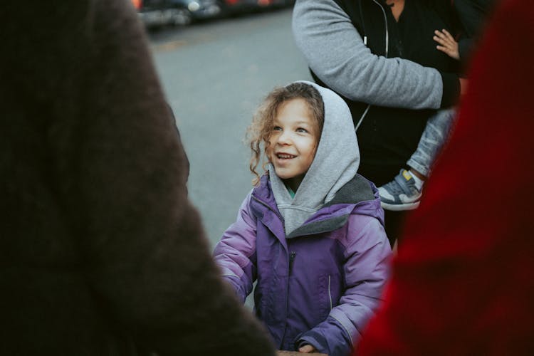 Happy Little Girl Among Adults On A City Street