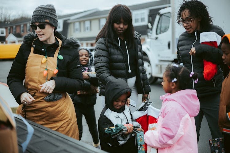 Volunteer Giving Presents To Children On A Christmas Event In City 