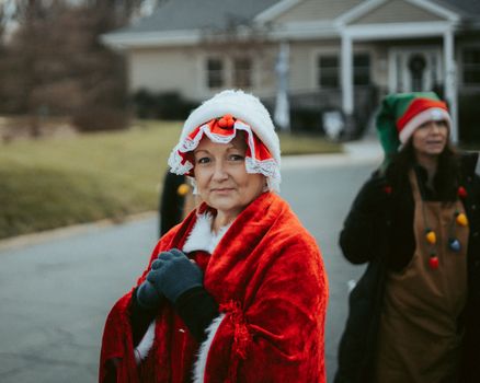 Women in festive costumes participate in a joyful Christmas parade outdoors.