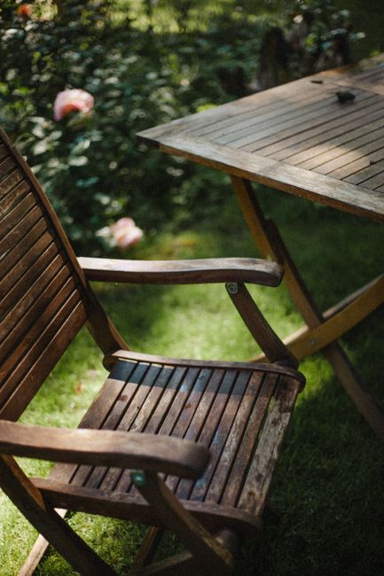 Wooden chair and table in a lush garden, perfect for outdoor relaxation.