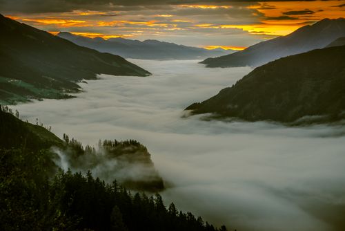 Free A stunning fog-covered valley in Vorderkrimml, Salzburg, captured during sunrise with mountains and trees. Stock Photo