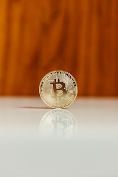 Close-up of a gold bitcoin coin on a reflective surface with a warm background.