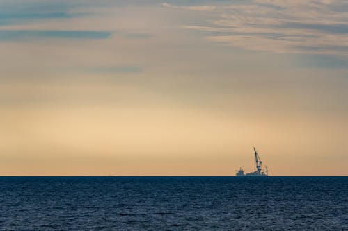 Ship with Crane in Sea on Sunset