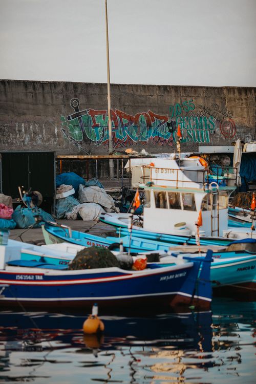 Free A lively harbor scene with colorful fishing boats and graffiti art creating a vivid waterfront atmosphere. Stock Photo