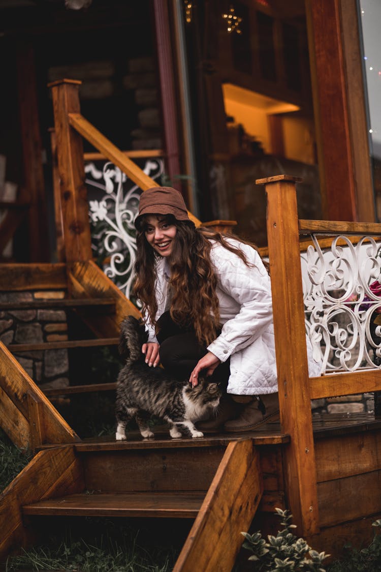 Happy Woman Stroking Cat On Wooden Stairs