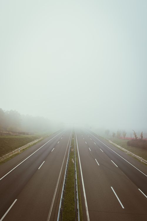 Free A deserted highway shrouded in fog creating a serene and mysterious atmosphere. Stock Photo