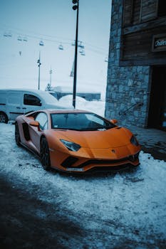 Stunning orange sports car parked outside a building on a snowy city street.