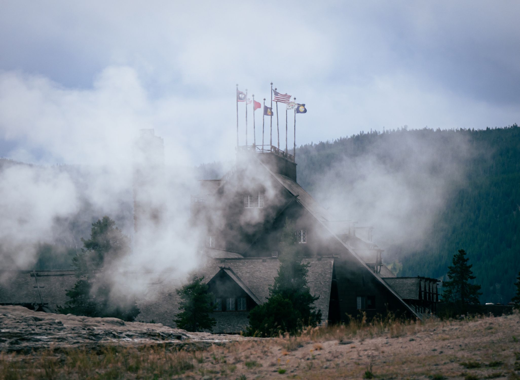 A misty lodge with flags, set against a tranquil forest mountain backdrop.