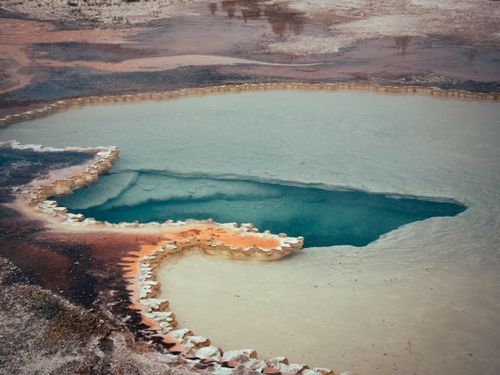 Free A stunning aerial view of a colorful natural hot spring in a barren landscape, showcasing vibrant mineral deposits. Stock Photo