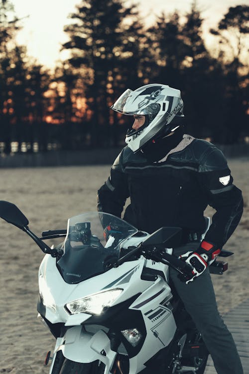 Man in Black Leather Jacket Riding on a White Kawasaki Motorcycle