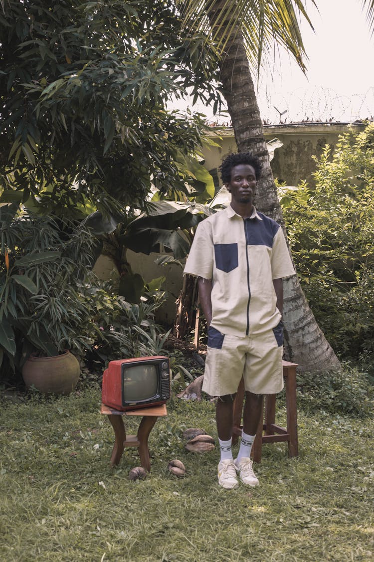 A Stylish Man Standing Beside A Television