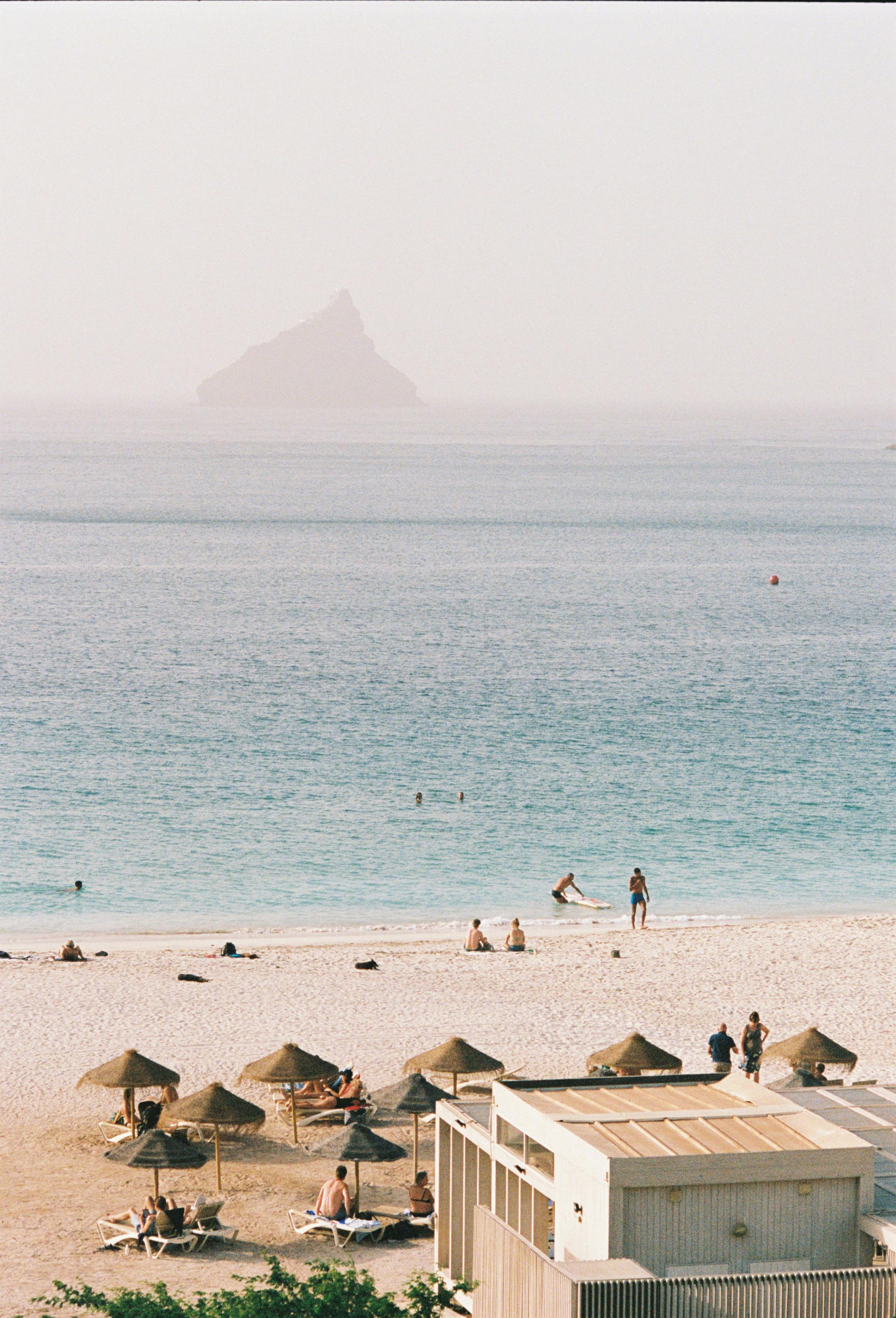 A beautiful beach scene in Praia, Cape Verde with people enjoying the sun and sea.