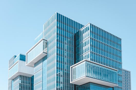 Striking contemporary glass building with unique geometric extensions under clear blue sky.