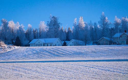 Free A serene winter scene featuring snow-covered houses and a blue sky. Stock Photo