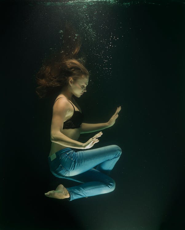 Fotografia Subaquática De Uma Mulher Vestindo Jeans E Sutiã Preto