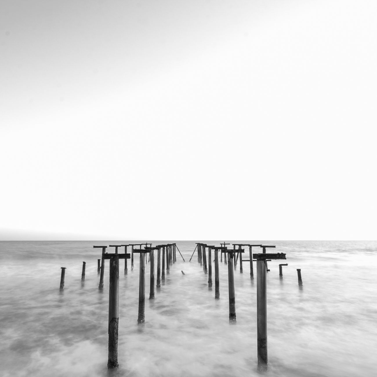 Captivating black and white long exposure of ocean jetty remains enveloped in misty water.. pexels, captivating, black