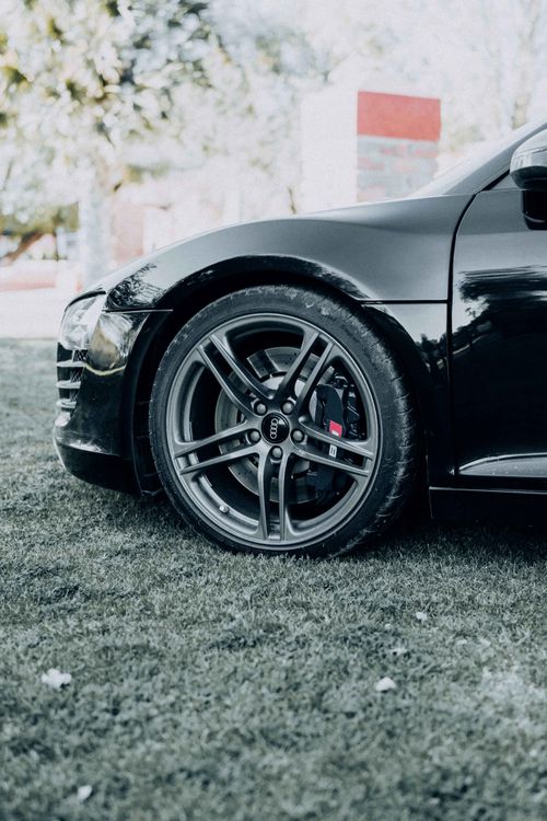 Free Detailed view of a black car's alloy wheel, captured outdoors on grass. Stock Photo