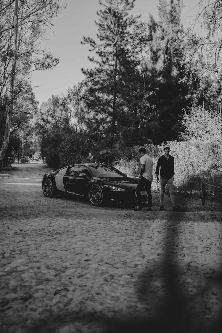 Two Guys Standing In Front Of A Car